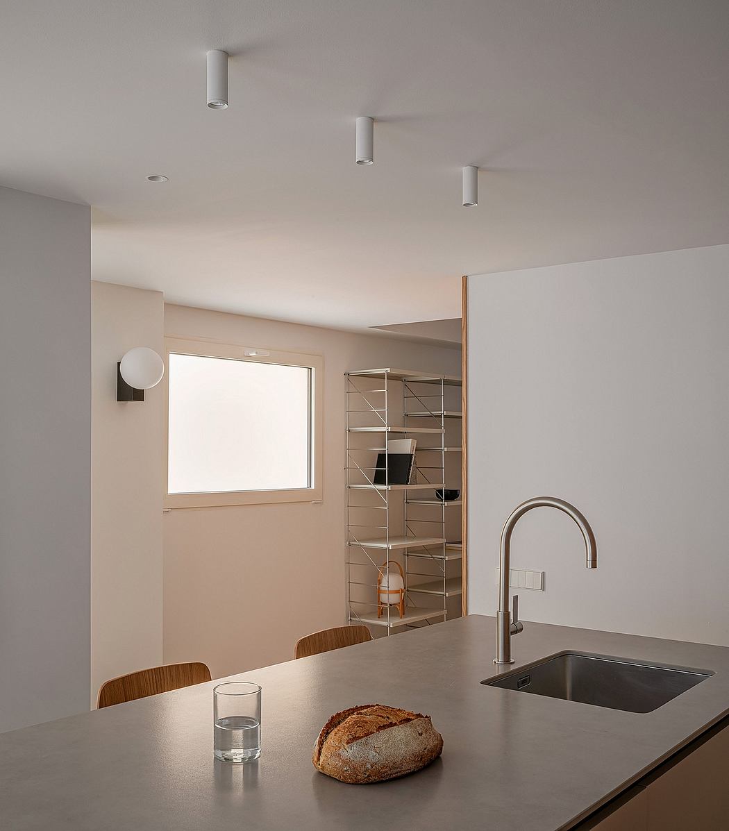 Modern kitchen with minimalist design, recessed lighting, and open shelving.
