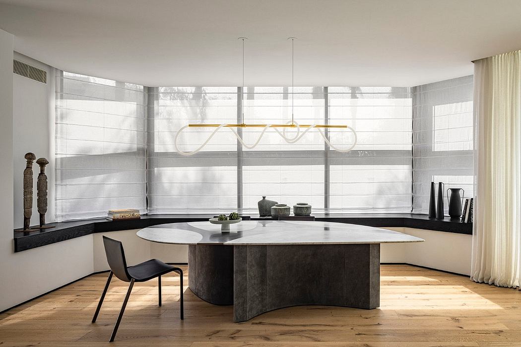 Sleek, modern dining area with curved table, pendant lighting, and expansive windows.