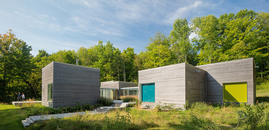 A modern, modular house with clean lines, vibrant colors, and expansive glass walls surrounded by lush greenery.