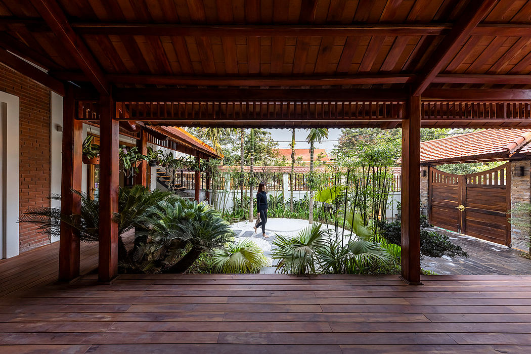 Wooden pavilion with tropical garden and paved pathways, showcasing architectural design.