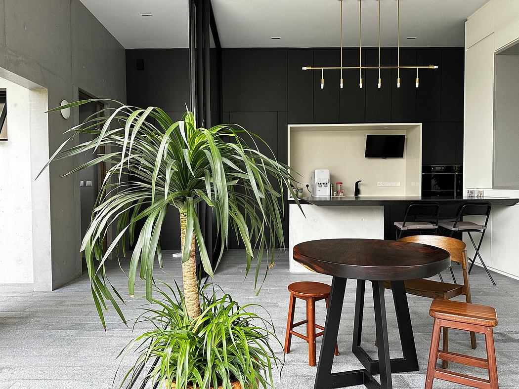 Minimalist kitchen interior with sleek black walls, wooden furniture, and lush greenery.