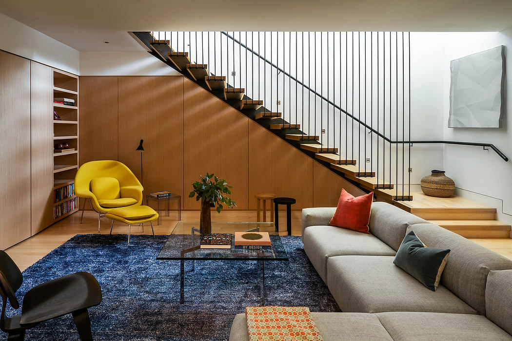 A modern, open-concept living space with a striking staircase, plush seating, and vibrant accents.
