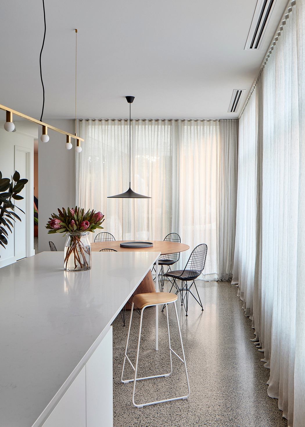 Minimalist dining space with sleek furniture, pendant lighting, and floor-to-ceiling curtains.