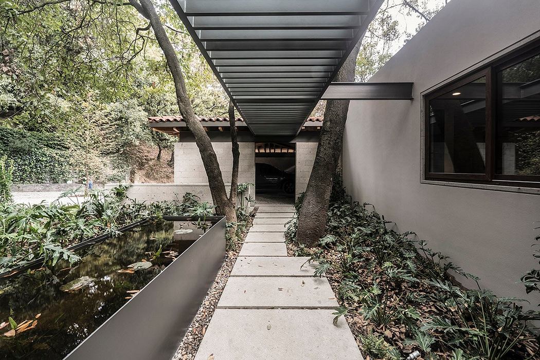 A contemporary design with a covered walkway, pond, and lush greenery.