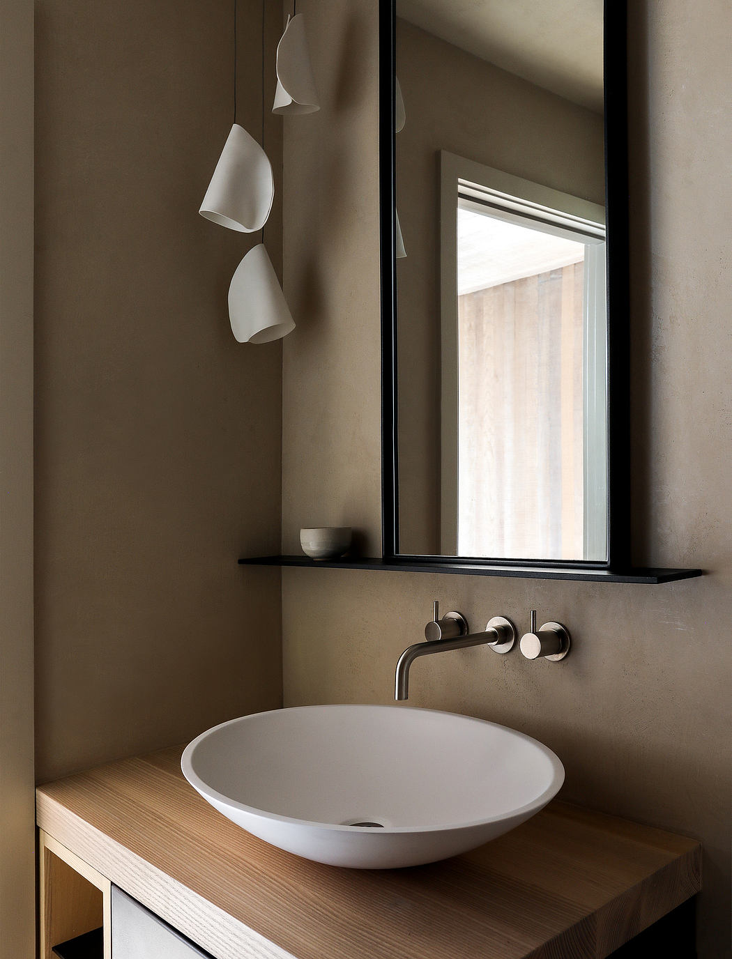 Modern bathroom with minimalist white sink, black faucet, and pendant lights.