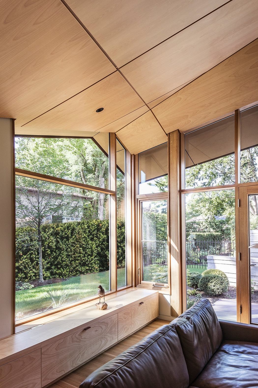 Spacious living room with expansive windows, wooden beams, and a cozy leather sofa.