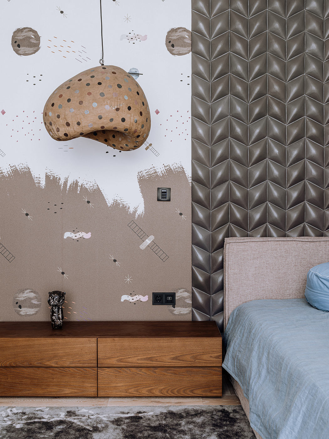 Geometric wall patterns, floating pendant light, wooden dresser, gray bedding.