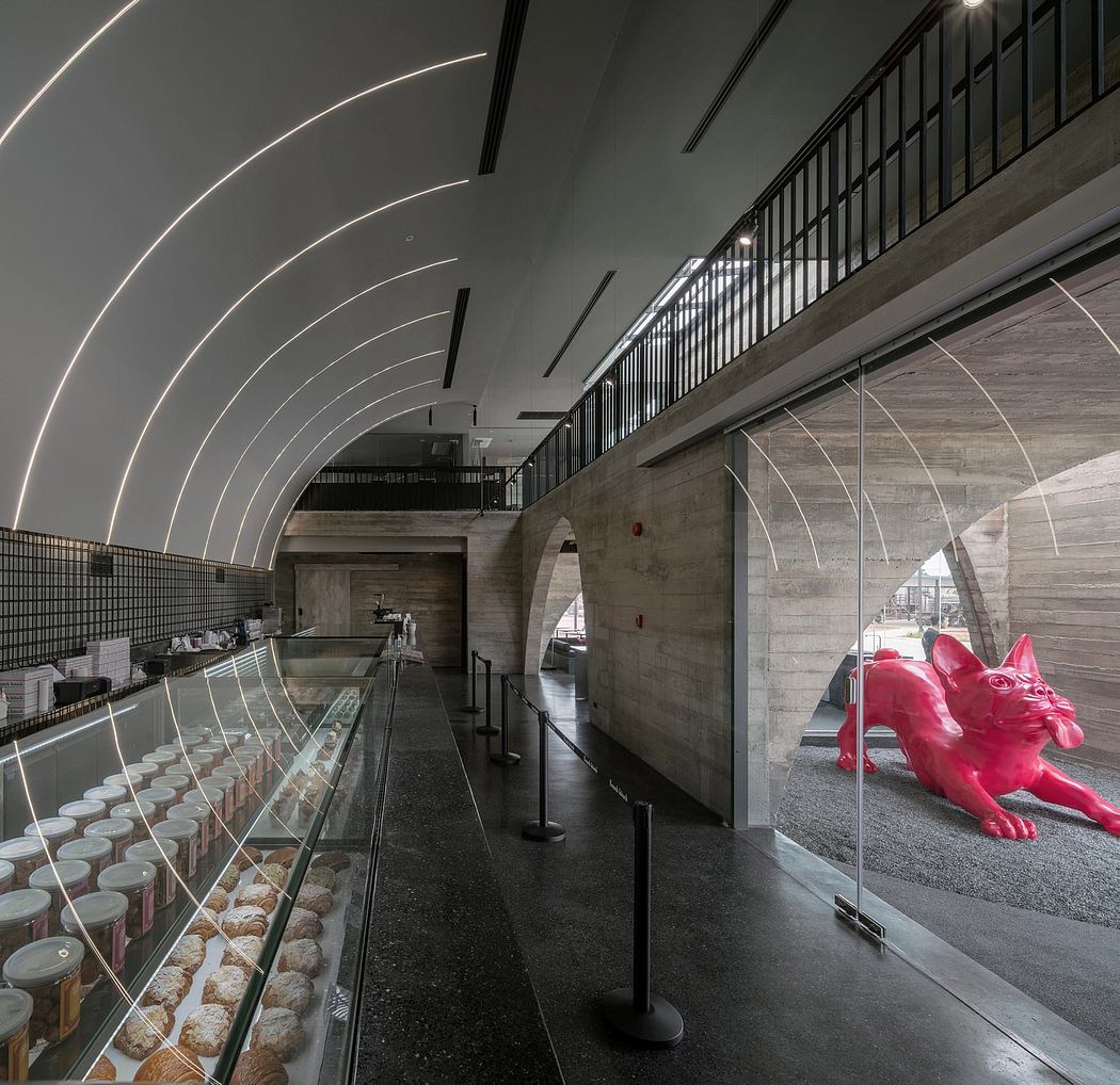 A modern, minimalist interior with arched ceilings, concrete walls, and a large red sculpture.