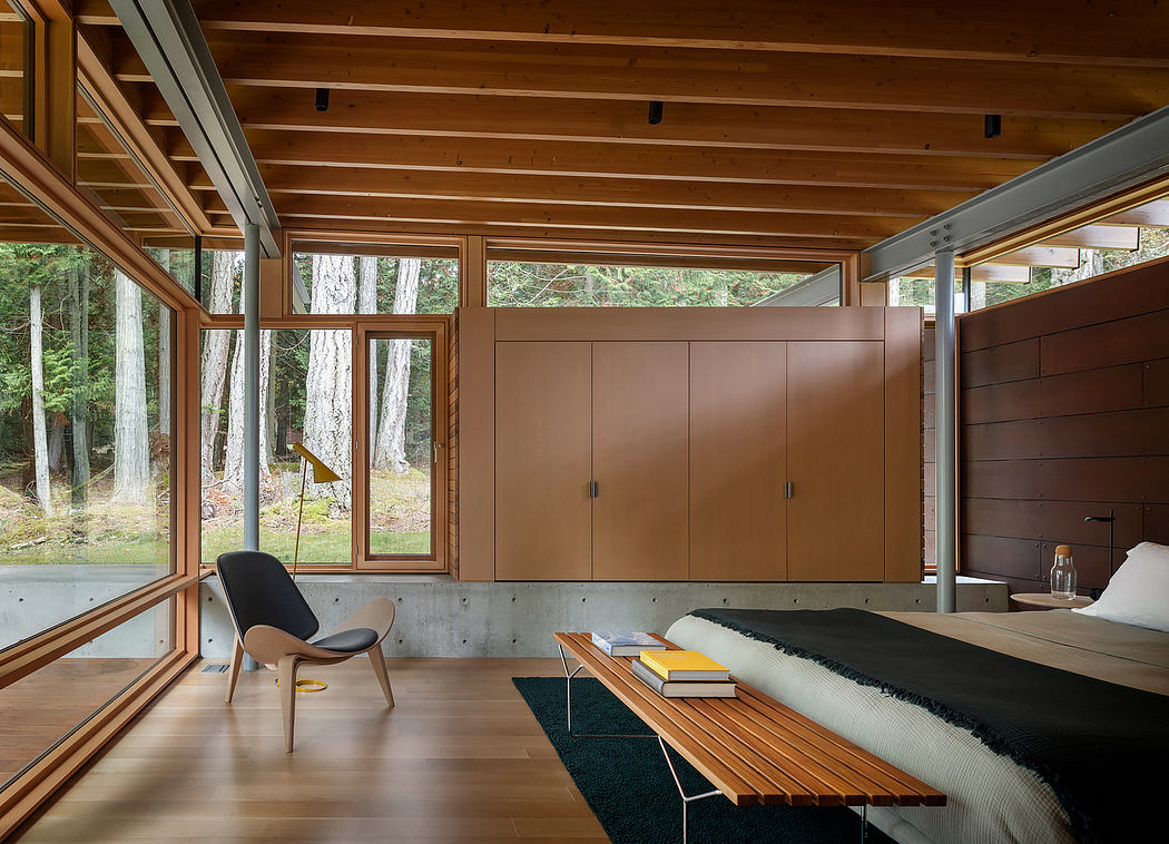 Cozy cabin interior with floor-to-ceiling windows, warm wood tones, and minimalist furnishings.