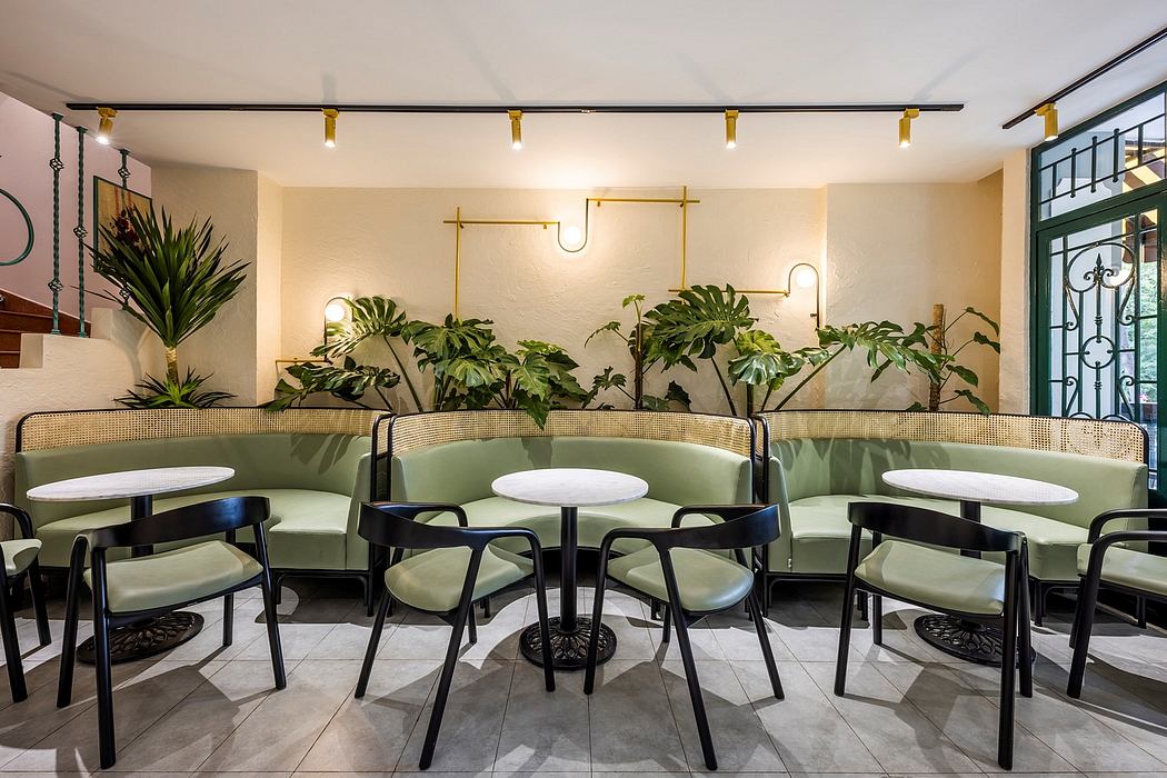 Modern cafe interior with sleek furniture, lush greenery, and track lighting creating a welcoming ambiance.