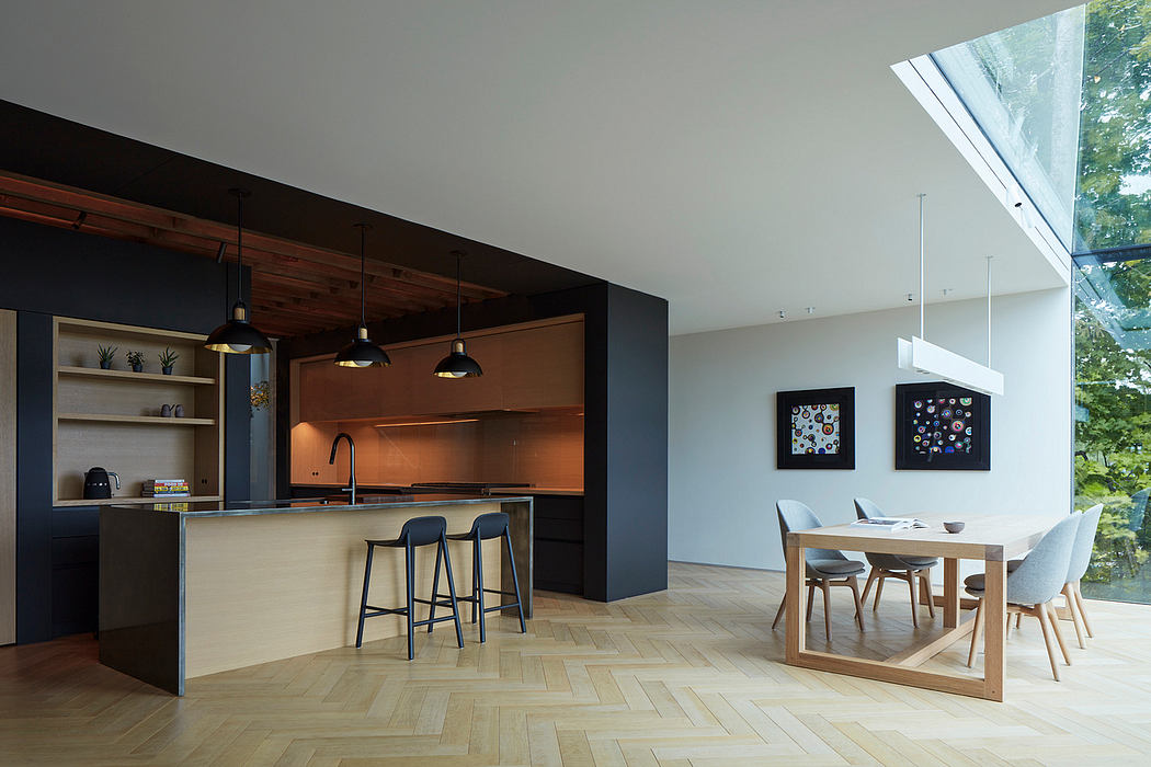 Sleek modern kitchen with black cabinetry, wood ceiling beams, and glass wall overlooking nature.