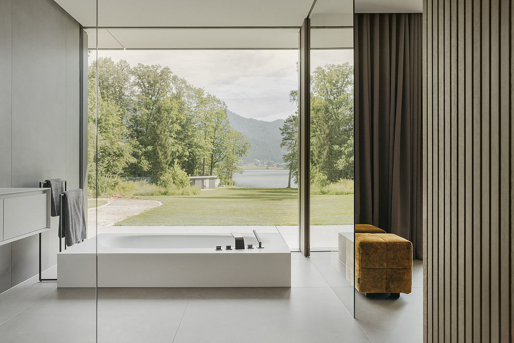 Expansive glass walls frame a serene lake and lush greenery, accentuating the clean, minimalist interior design.