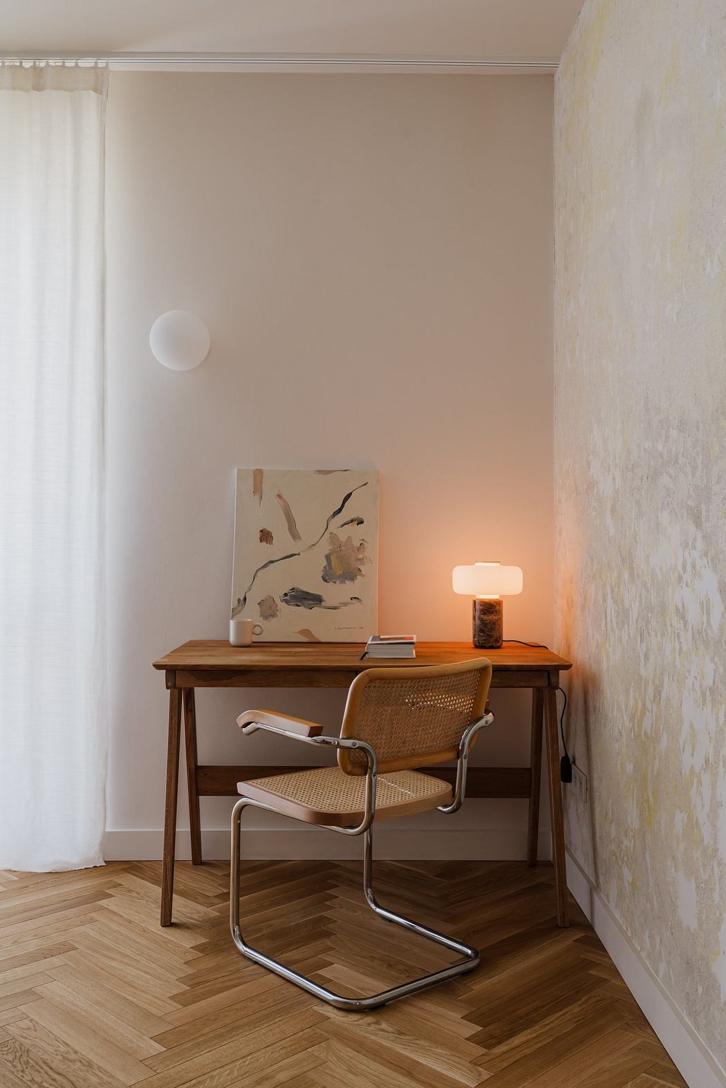Cozy home office with wooden desk, cane chair, and abstract art on the wall.