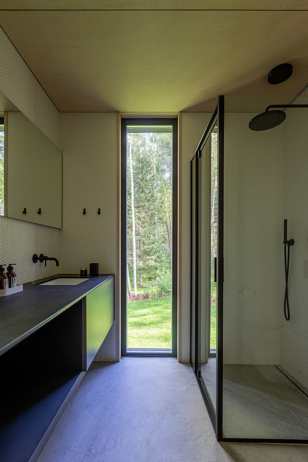 Minimalist bathroom with a narrow window, dark vanity, and modern shower fixtures.