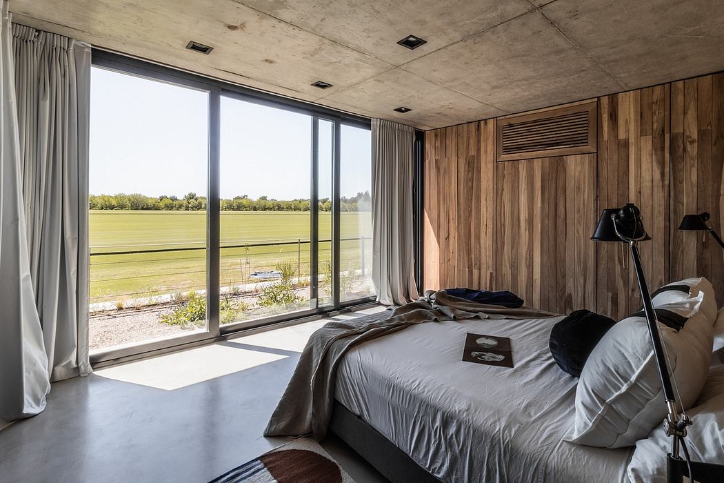 Spacious bedroom with wood-paneled walls, large windows overlooking a field.