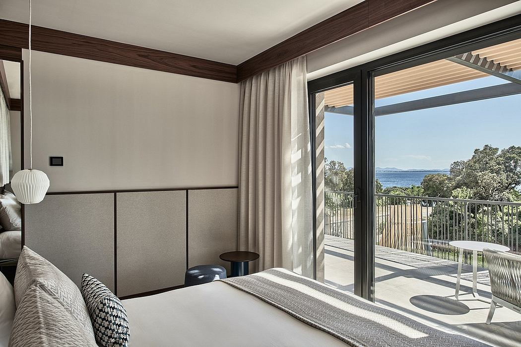 Modern bedroom with large sliding glass doors leading to a balcony and scenic ocean view.