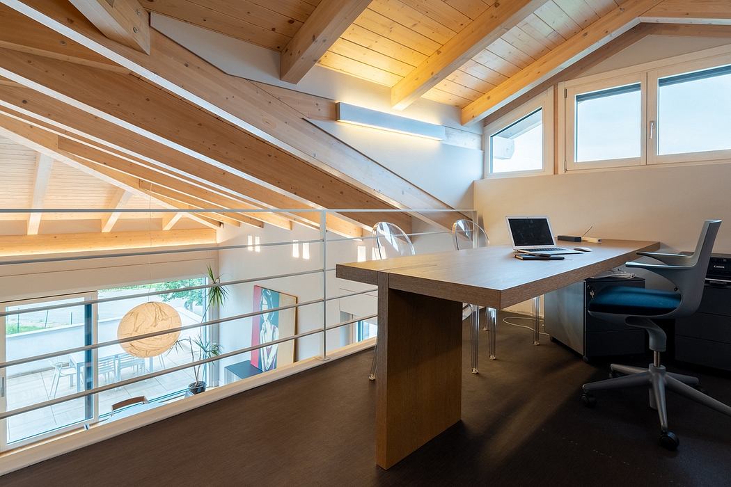 Expansive, modern home office with exposed wood beams, large windows, and a minimalist desk.