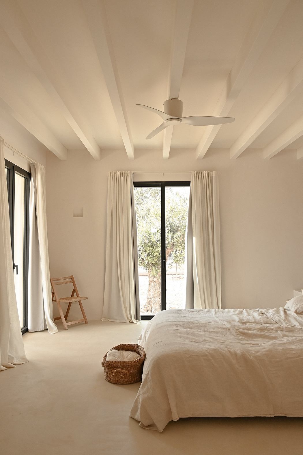 Serene bedroom with high ceilings, minimalist decor, and floor-to-ceiling windows.