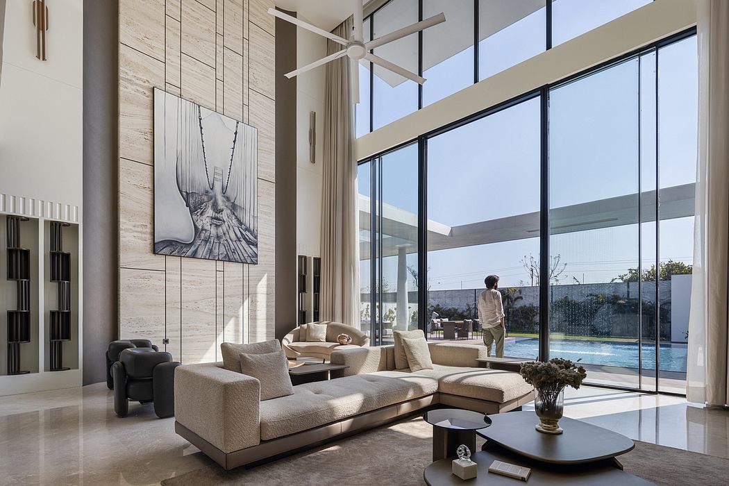 A spacious modern living room with floor-to-ceiling windows, sleek furnishings, and a striking artwork.