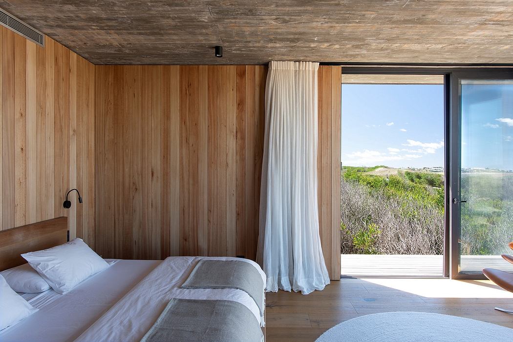 Rustic bedroom with floor-to-ceiling wood paneling, large window offering scenic view.