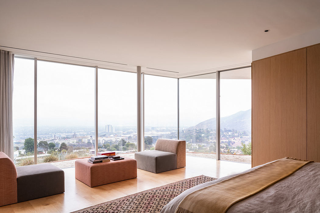 Spacious modern room with floor-to-ceiling windows offering panoramic city views and minimalist furnishings.