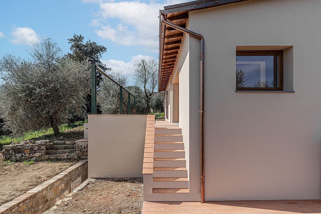 Exterior of modern log cabin-style house with wooden stairs, trees, and stone wall.