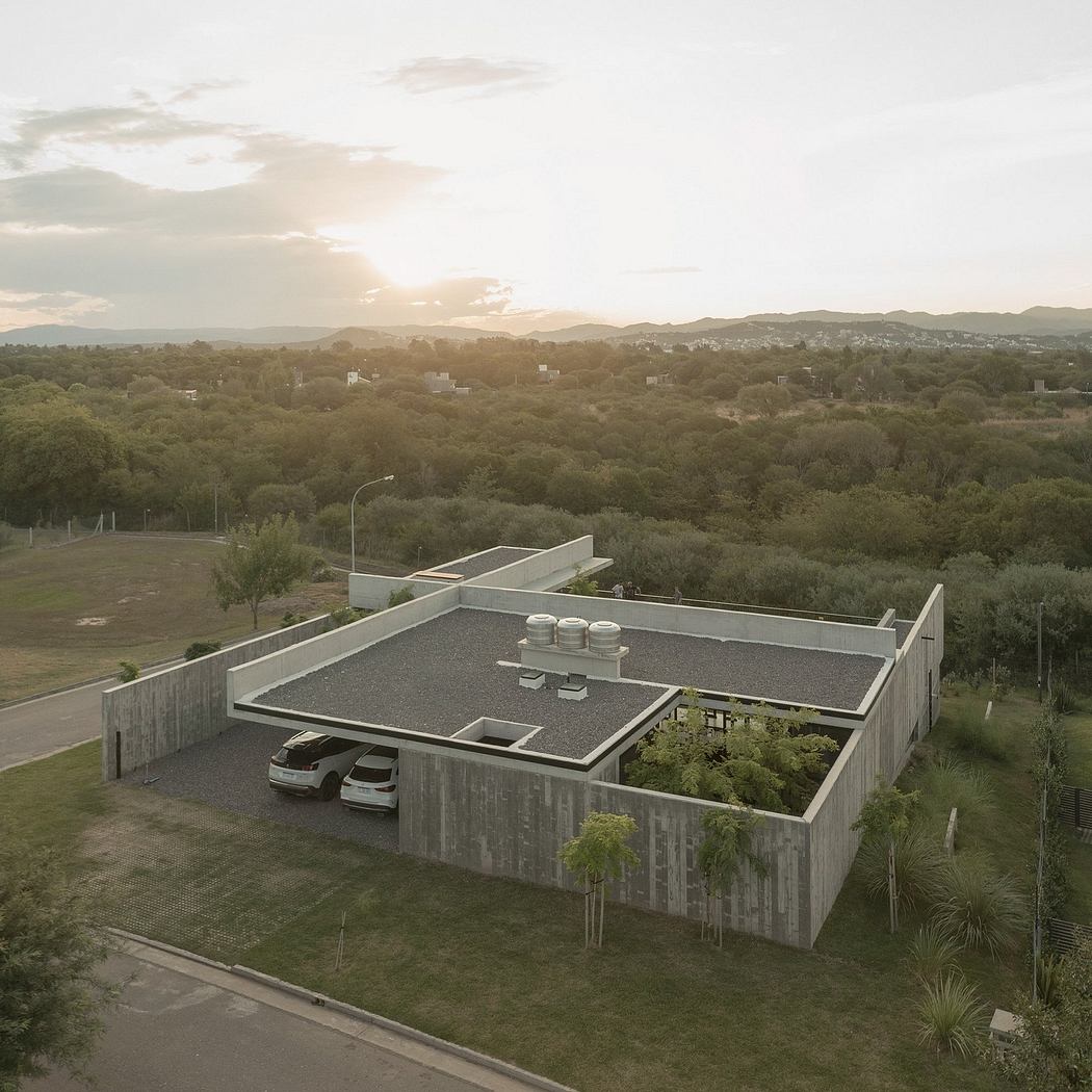 A modern architectural structure with a flat roof, surrounded by lush greenery and mountains.