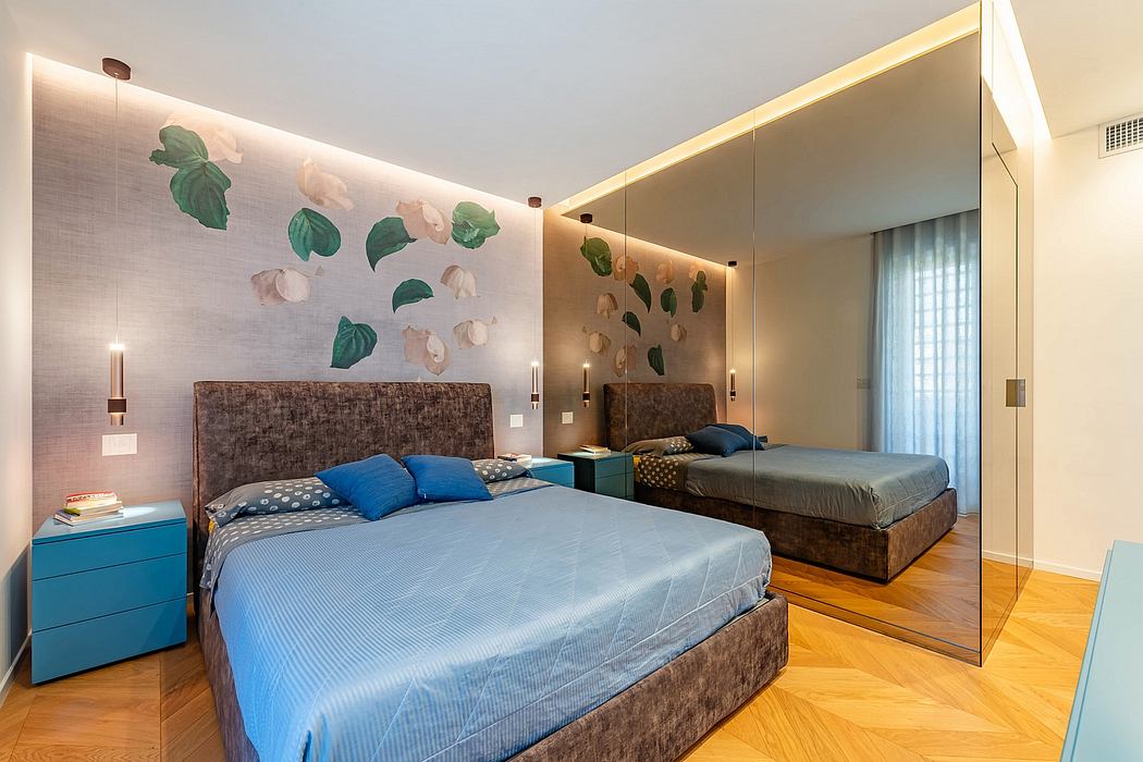 A modern bedroom with a large mirror wall, leafy wall art, and wooden flooring.