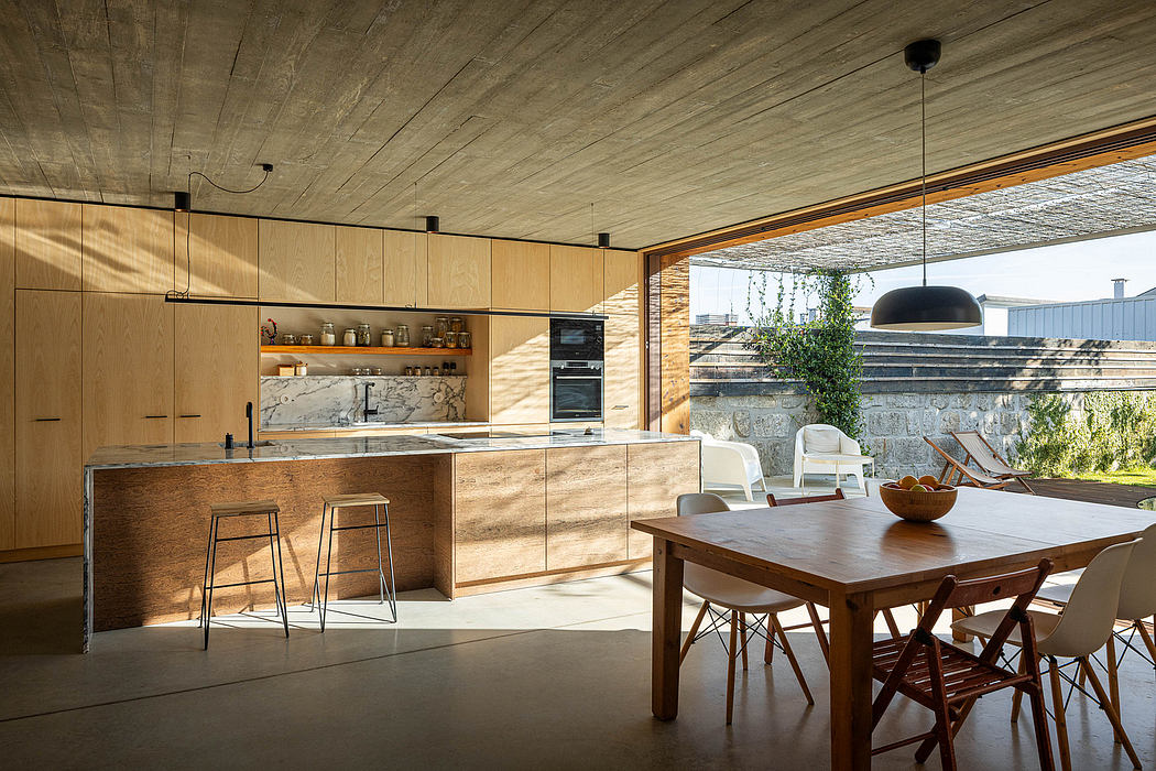 Minimalist kitchen and dining area with wooden details, concrete ceiling, and outdoor view.