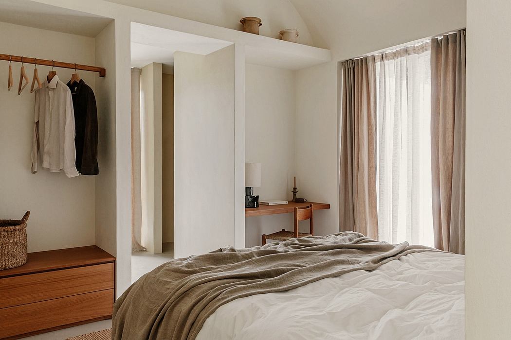 A cozy, minimalist bedroom with warm wooden furnishings and soft, neutral tones.