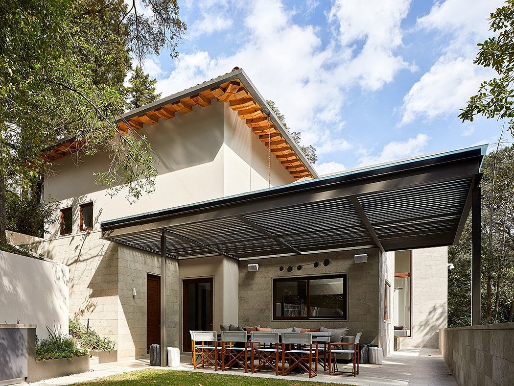 A modern, rustic-style home with a large covered patio, wooden beams, and lush greenery.