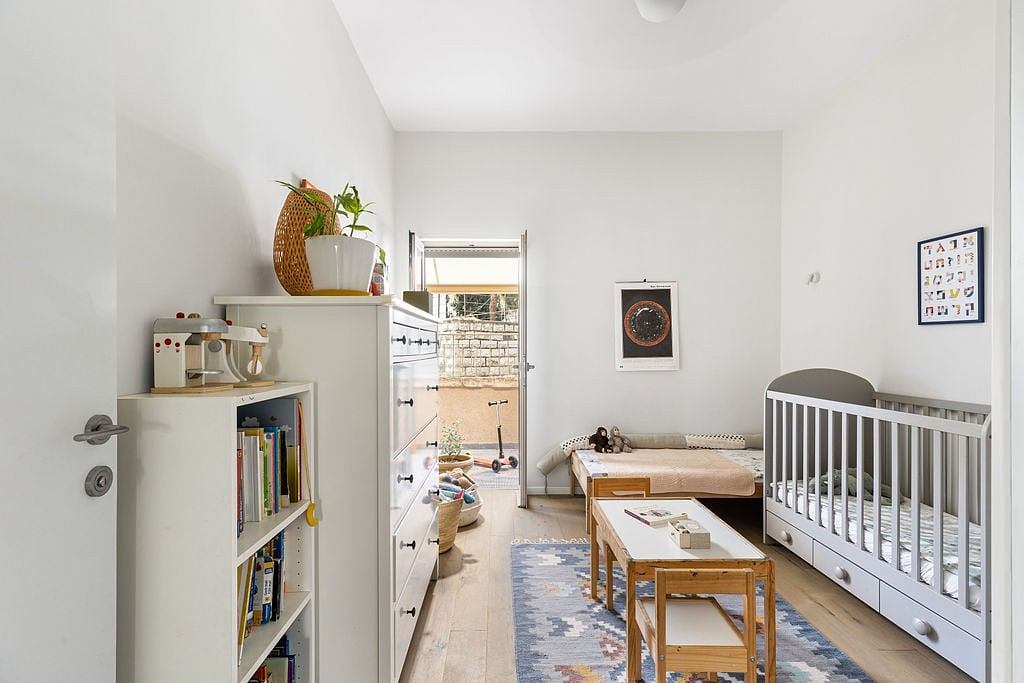 A cozy nursery with a warm, minimalist design featuring wooden furniture and decor.