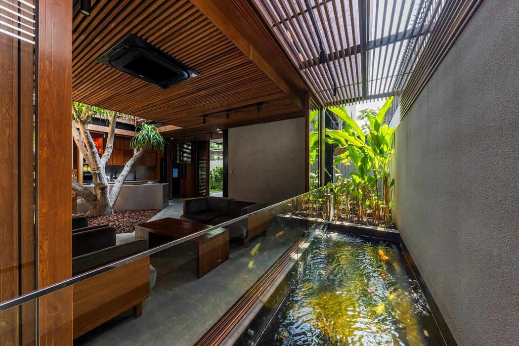 Inviting tropical-inspired interior with lush greenery, wooden accents, and a tranquil water feature.