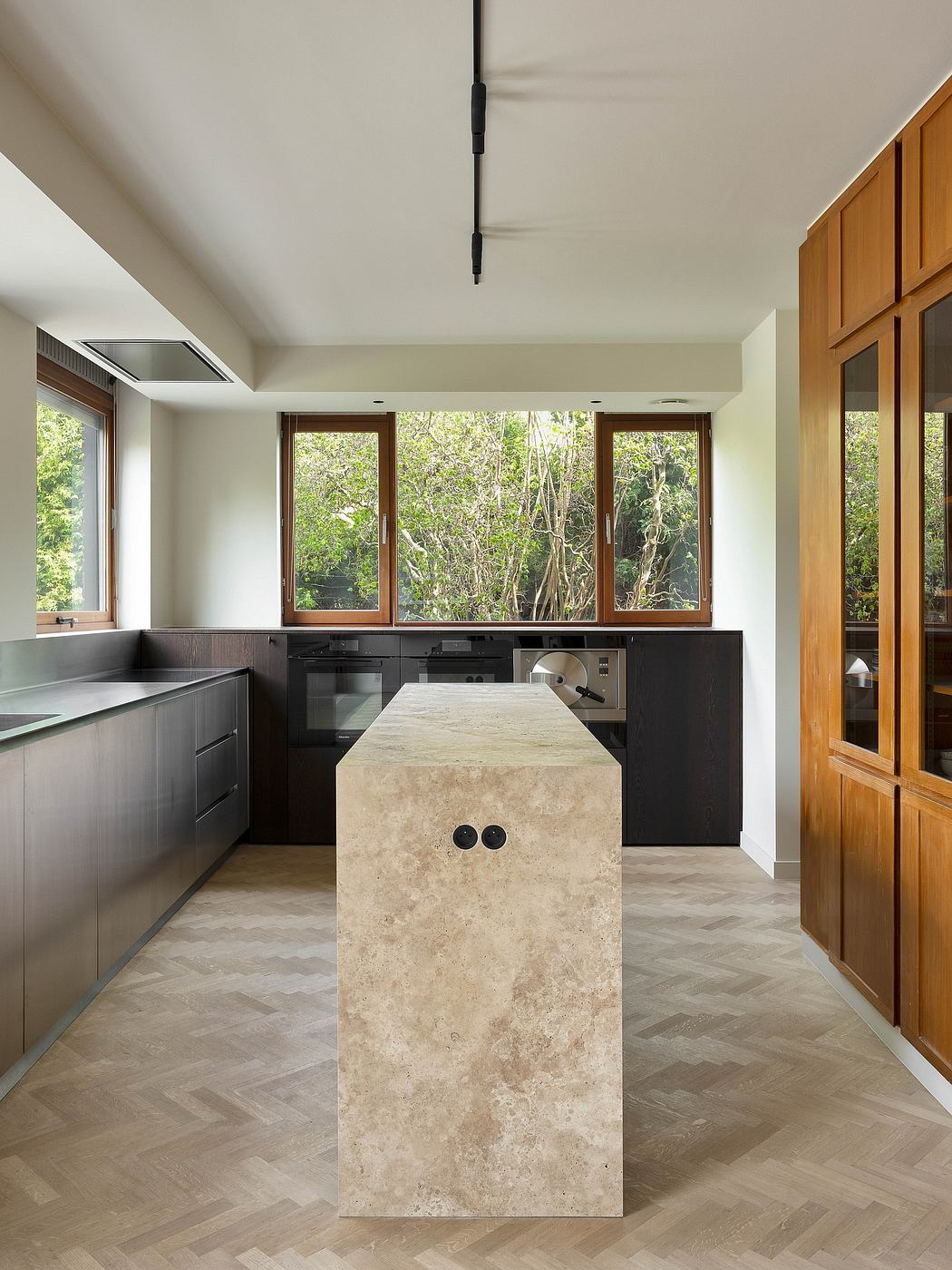 Sleek, modern kitchen with a marble island, wood cabinetry, and expansive windows overlooking nature.
