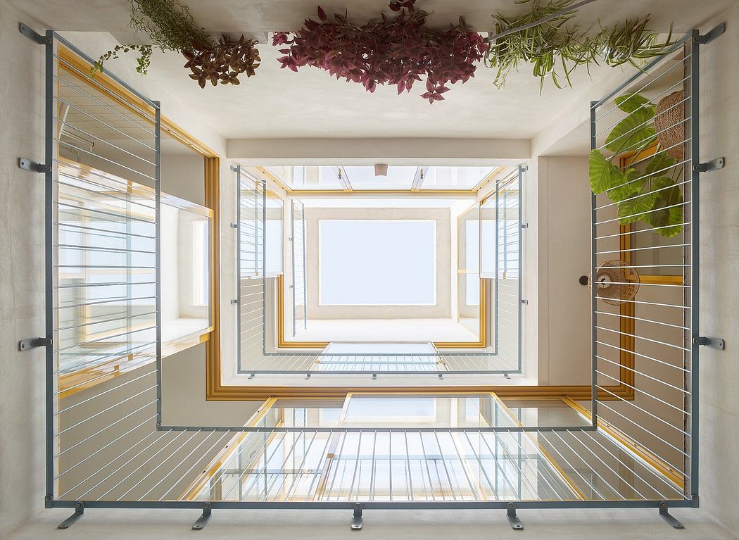 A modern, open-concept interior with glass walls, wooden beams, and hanging greenery.