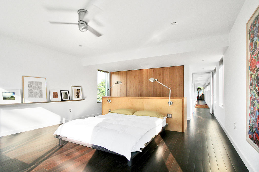 Spacious bedroom with modern wooden headboard, artwork display, and gleaming wood flooring.
