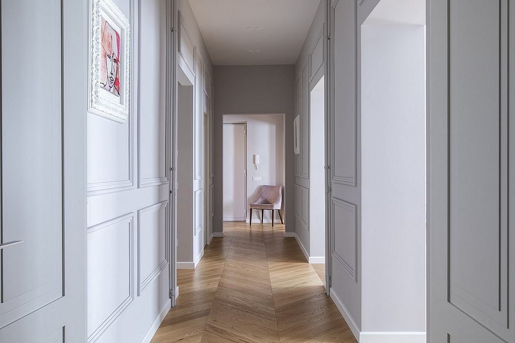 A bright, minimalist hallway with wooden herringbone floors and recessed lighting.