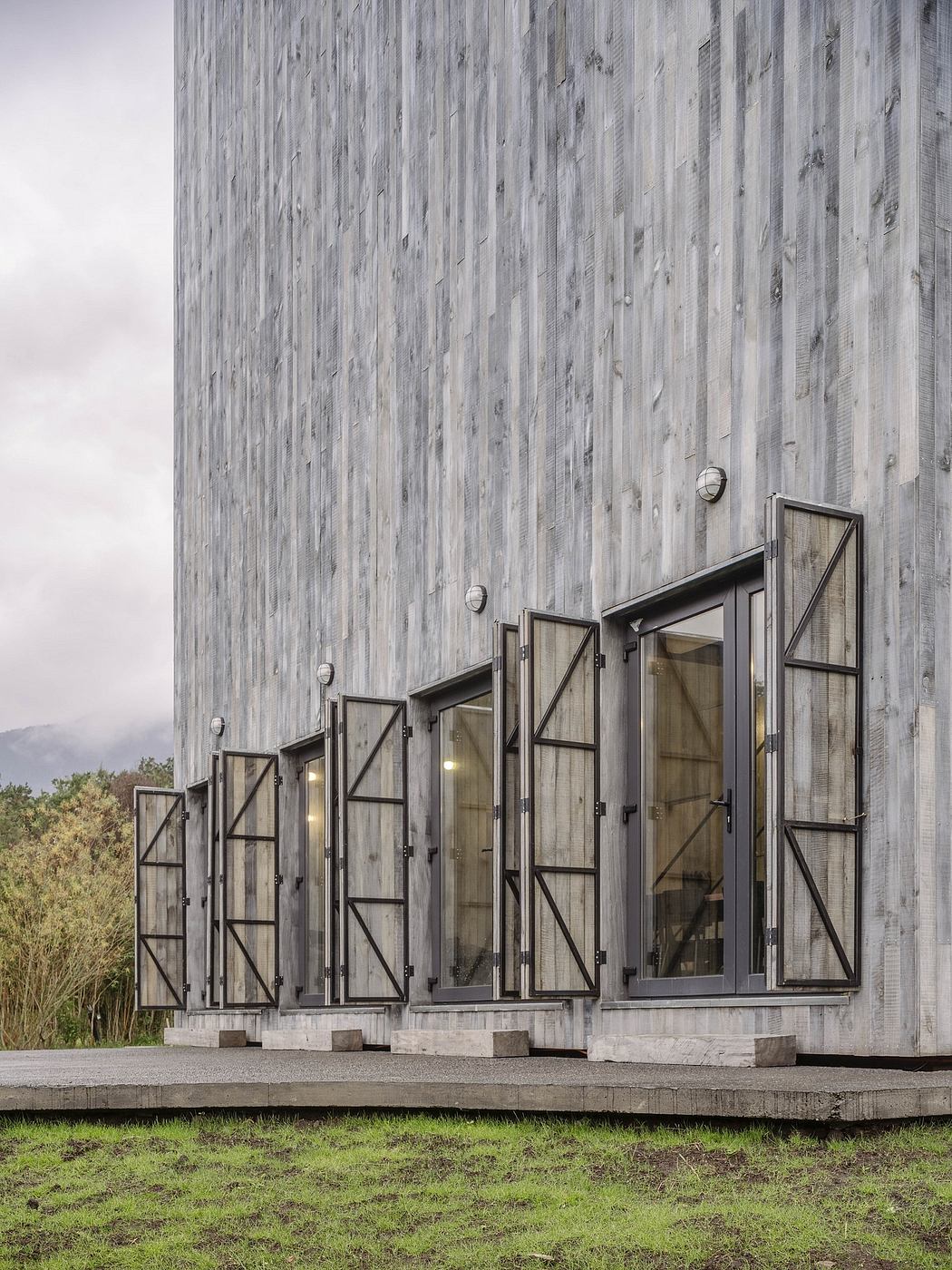 A modern architectural structure with triangular windows and a weathered wooden façade.