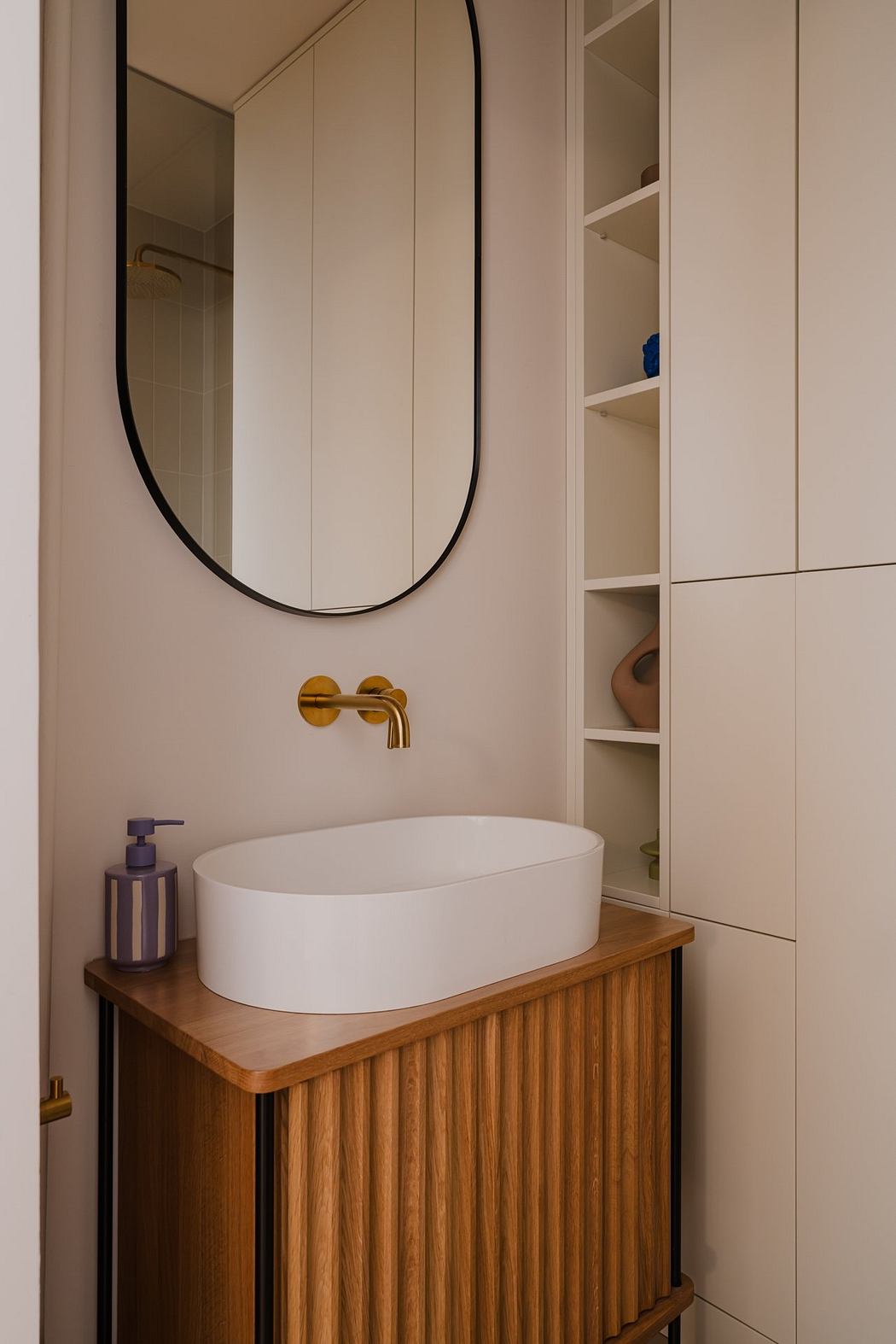 Modern bathroom with minimalist white vanity, wooden accents, and oval mirror.