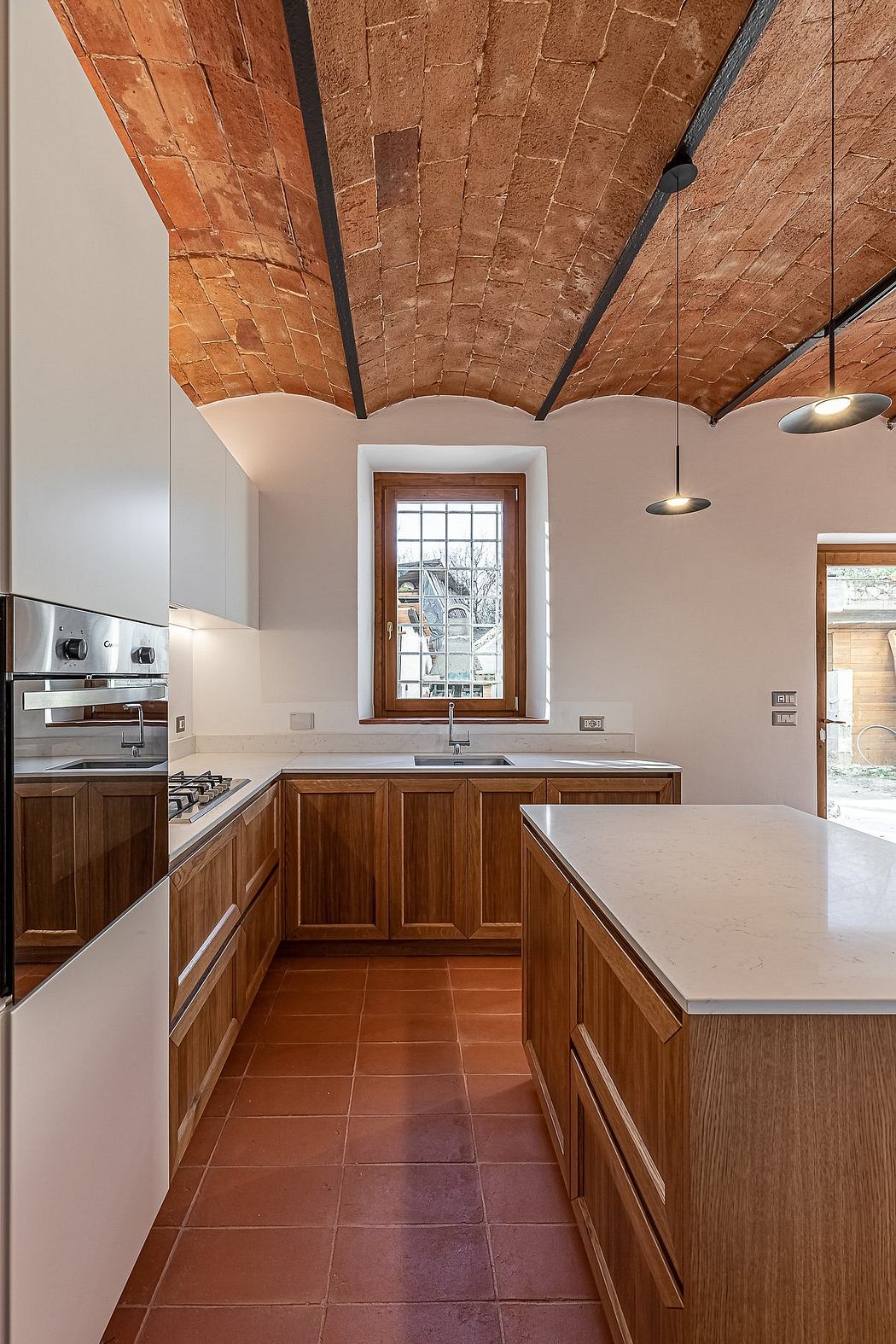 A modern kitchen with wooden cabinetry, stone countertops, and a vaulted brick ceiling.
