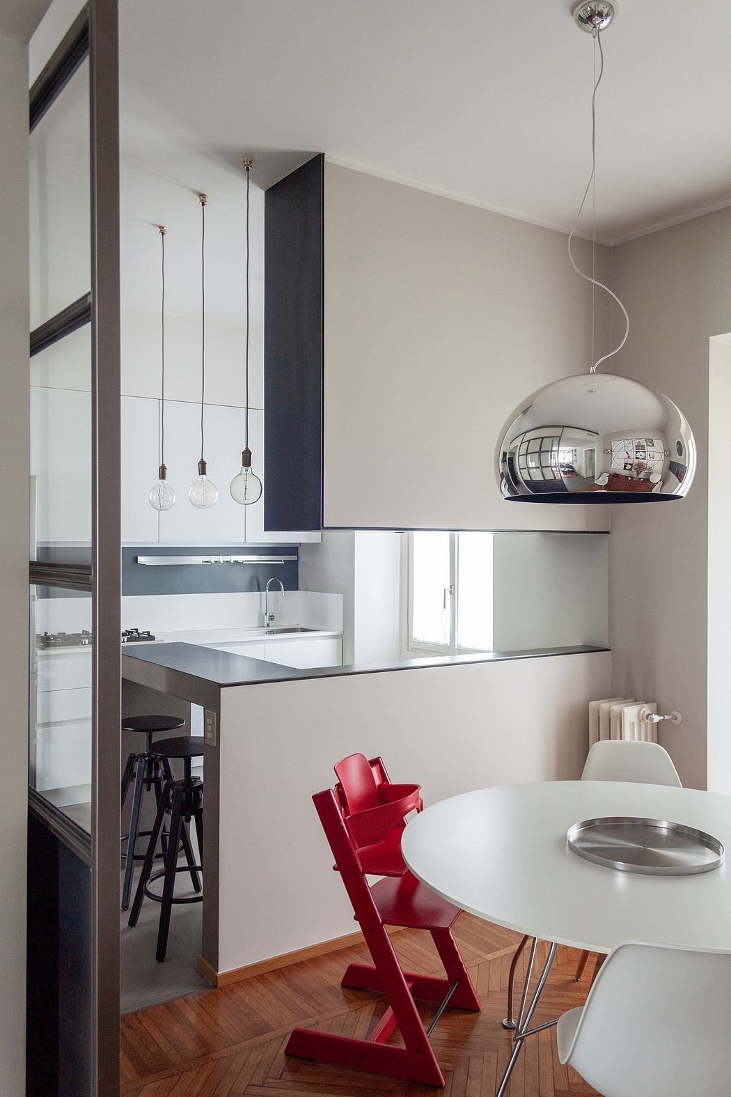 Sleek modern kitchen with pendant lights, mirror-finish dome light, and red accent chairs.