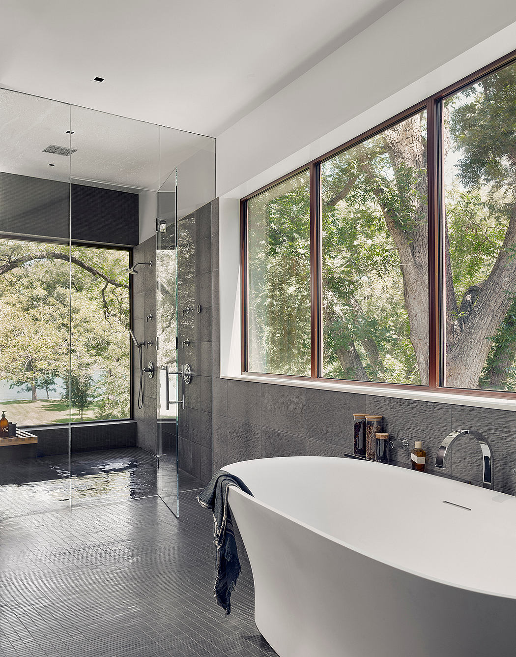 Spacious bathroom with floor-to-ceiling windows, sleek tiled walls, and a modern freestanding tub.