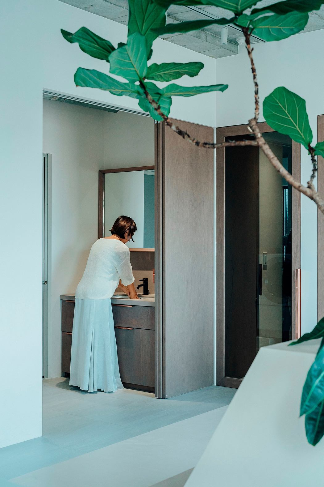 A modern, minimalist interior with lush greenery and a person in the background.