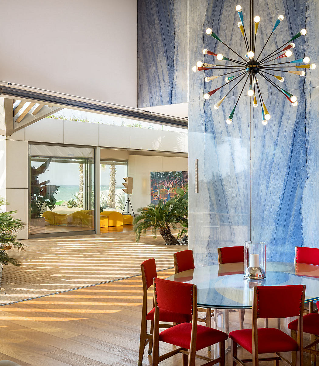 Spacious and modern interior with vibrant decor, floor-to-ceiling windows, and a striking multi-colored chandelier.