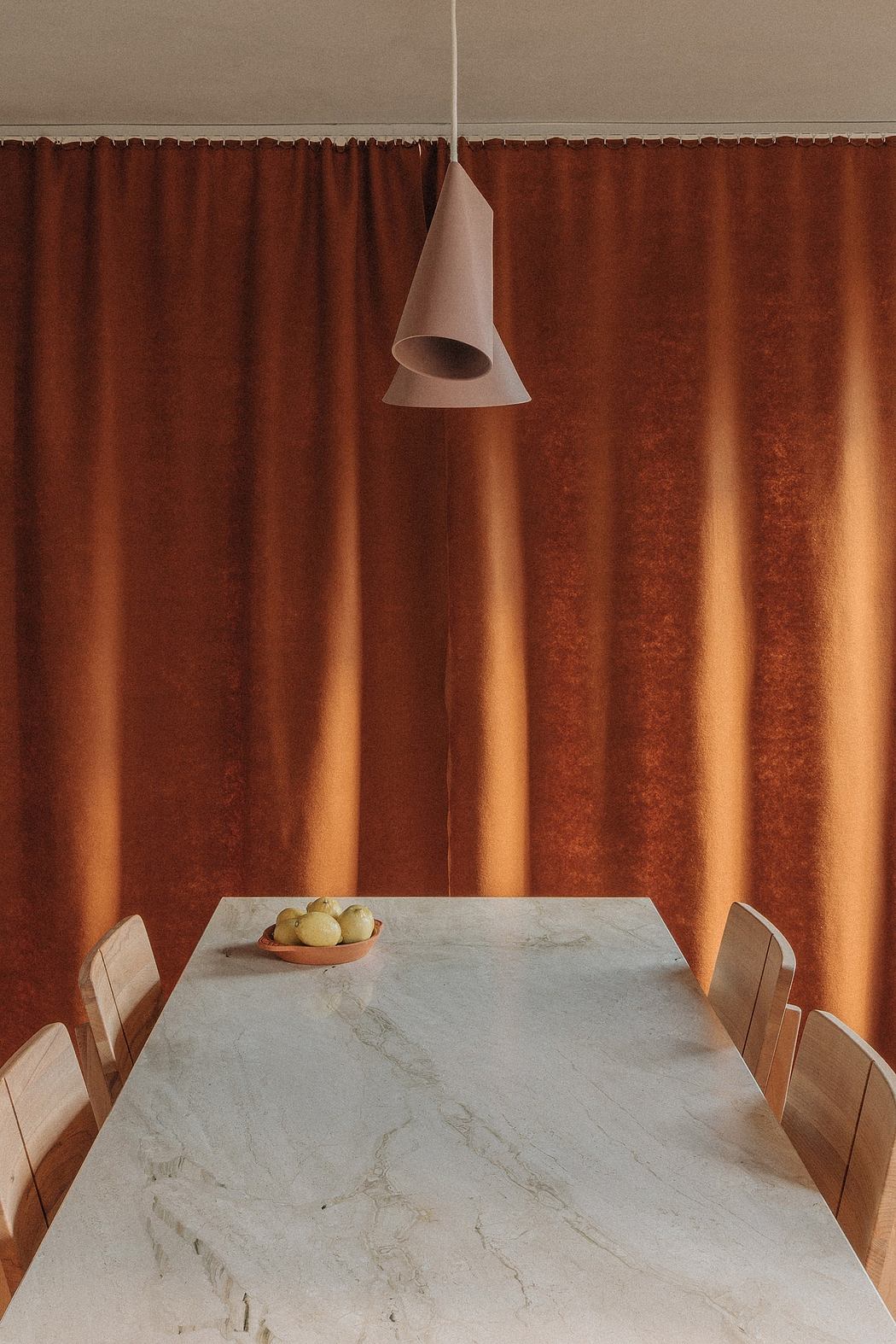 Warm-toned curtains, marble-topped table, and modern pendant light create a cozy ambiance.