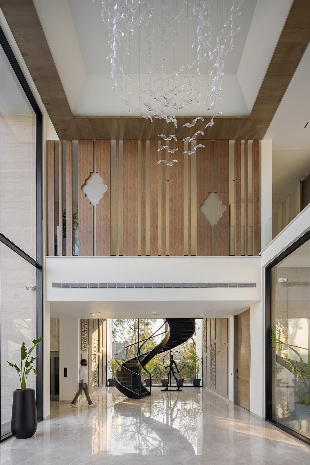 Spacious lobby with wood paneling, glass chandelier, and spiral staircase.