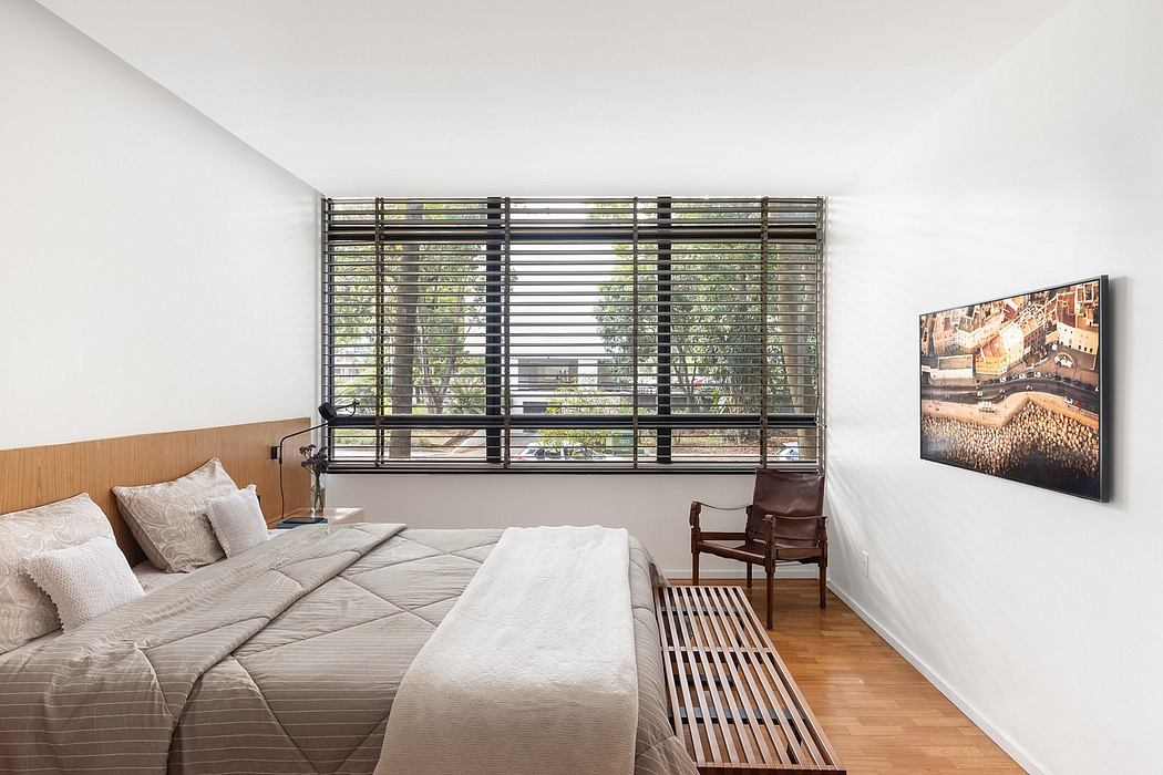 Minimalist bedroom with large window, slatted blinds, and artwork on the wall.