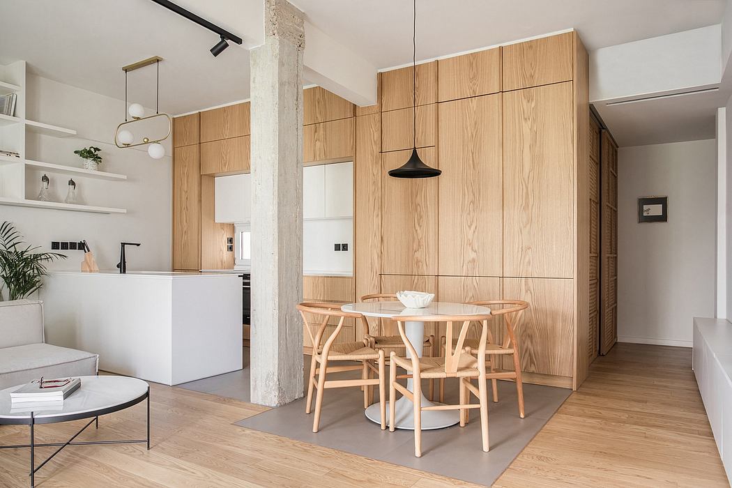 A modern, minimalist kitchen with wooden cabinetry, pendant lighting, and a round dining table.