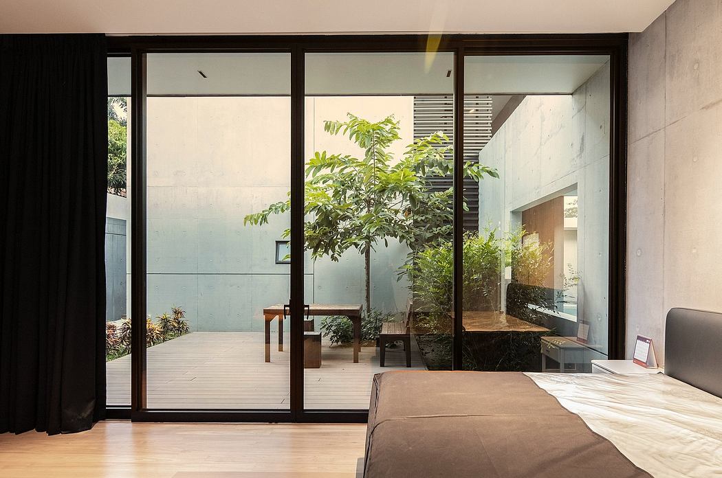 A modern interior with glass walls, a wooden table, and lush greenery outside.