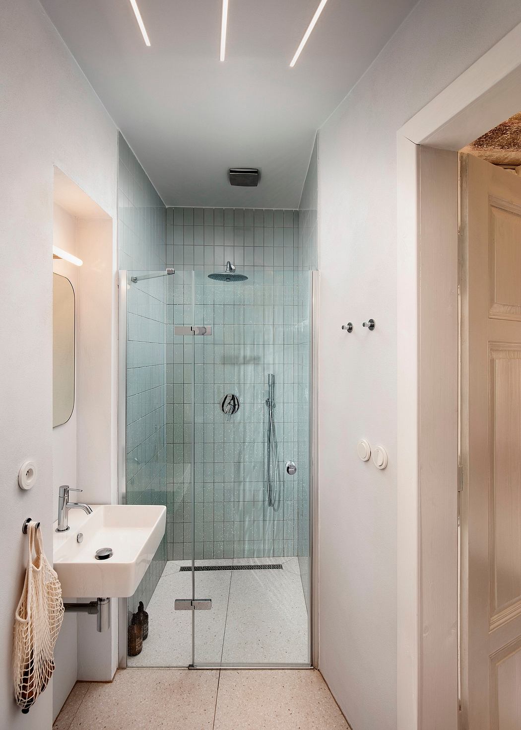 Modern minimalist bathroom with glass-enclosed shower, sleek vanity, and recessed lighting.